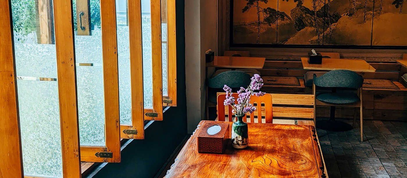 Mesa de madeira posta em restaurante japonês, com biombo e janelas de shoji ao fundo